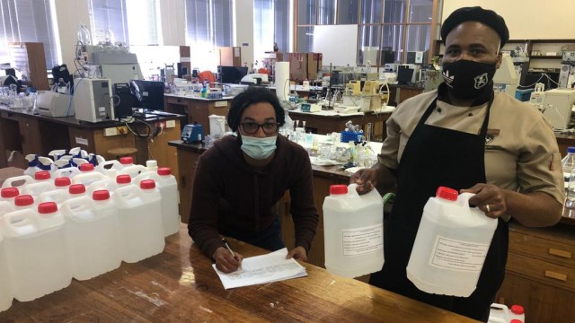 Ronn Mager and Siyasanga Nkuna from Residential Operations at Rhodes University collect hand sanitiser from the Pharmacy Faculty to start preparations for the next group of returning students